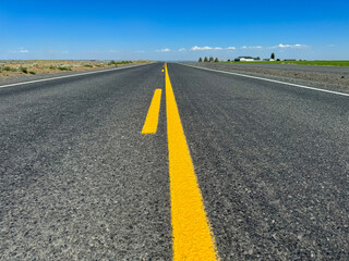 Obraz premium Road to nowhere. Empty rural asphalt road with yellow lines among fields