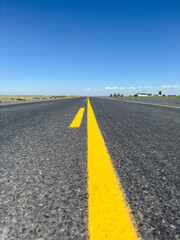 The road to the sky. Empty rural asphalt road with yellow lines among fields