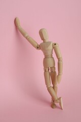 Wooden human model on pink background. Mini mannequin