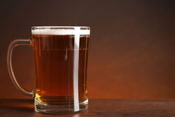 Mug with fresh beer on wooden table against color background. Space for text
