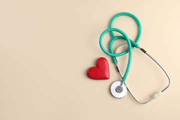 Stethoscope and red heart on beige background, top view. Space for text