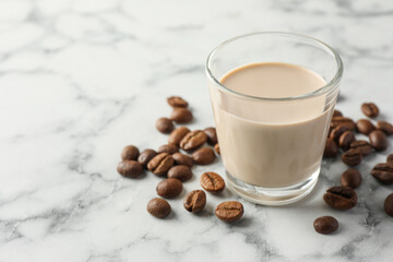 Coffee cream liqueur in glass and beans on white marble table, space for text