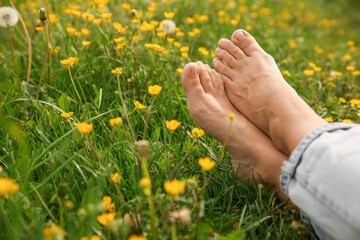 Woman sitting barefoot on green grass outdoors, closeup. Space for text