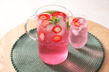 Freshly made strawberry lemonade with mint in jug and glass on wooden table