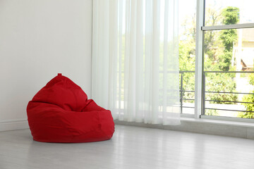 Red bean bag chair near window in room. Space for text