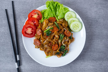 Kwetiaw or Kwetiau, fried rice noodles with sausage, egg and vegetables. Perfect for recipe, article, catalogue, promotion, or any cooking contents.