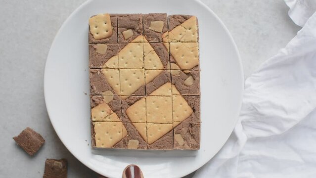 Overhead view of chocolate fudge with cookies and fudge pieces on a white plate, Top view of hazelnut chocolate fudge cut into pieces, fudge cookie candy on a white granite countertop