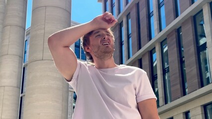 Young tired thirsty man is suffering of heat at summer sunny day, having sunstroke outdoors