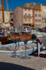 Glasses of cold rose Cote de Provence wine in old fisherman boats and yacht harbour in Saint-Tropez, summer vacation on French Riviera in Provence, France
