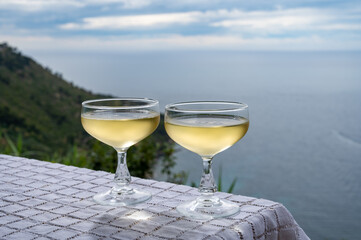 Cold sparkling wine, cava or champagne in two coupe glasses on table with sea water view