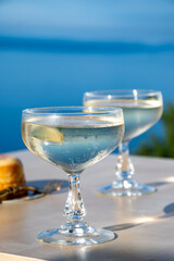 Cold sparkling wine, cava or champagne in two coupe glasses on table with blue sea water view, French Riviera is summer, France
