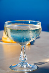 Cold sparkling wine, cava or champagne in coupe glass on table with blue sea water view