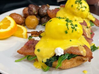 Plate of eggs benedict with side of potatoes 