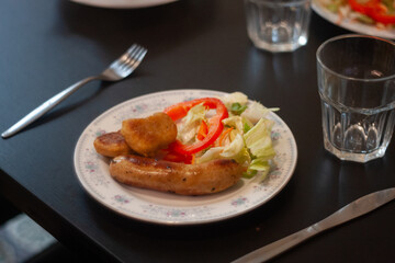 dinner table with chicken nuggets, sausages, fries and salad.