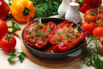 Tasty stuffed peppers in dish and ingredients on white wooden table