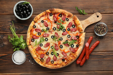 Tasty pizza and ingredients on wooden table, top view