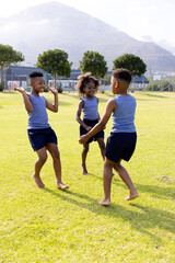 Happy african american schoolchildren playing football on field at school