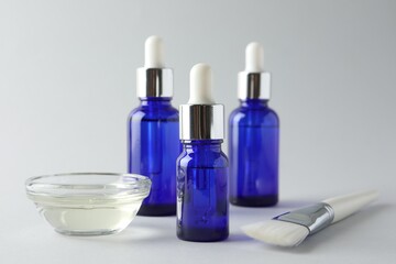 Bottles of chemical peel, bowl with liquid and brush on light background, closeup. Peeling procedure