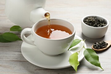 Pouring refreshing green tea into cup at grey wooden table, closeup