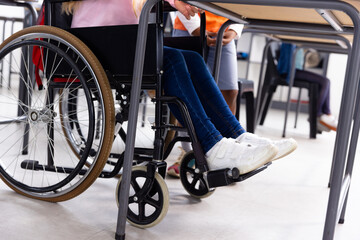 Fototapeta premium Diverse schoolgirl in wheelchair with her friend in school classroom