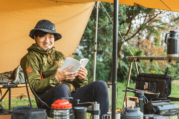 秋冬のキャンプ場でソロキャンプする男性キャンパー（読書・本を読む）
