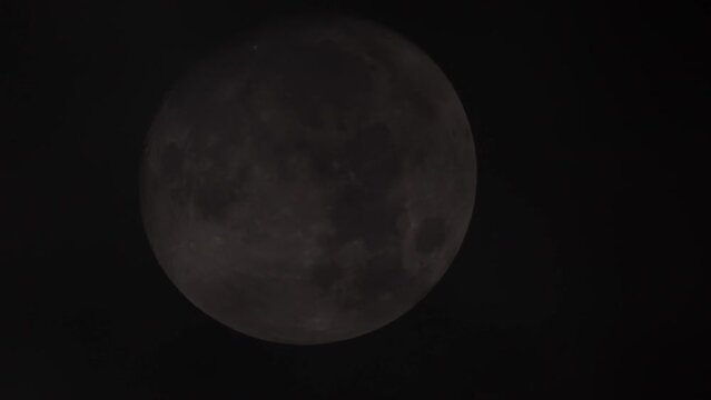 Full moon at dark lightly cloudy night. Clouds moving by the moon, Halloween horror spooky atmospheric view in dark night sky. Mystery fairyland, werewolf moon witchcraft concept.