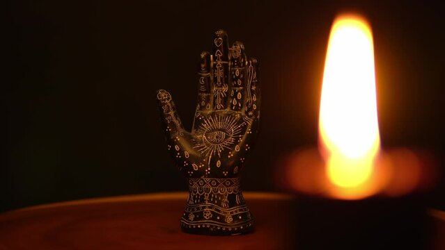 Mystical esoteric table with ritual object. Fortune teller palm with black candles on tree trunk surface. Prediction destiny and forecasting future hand reader statue. Occult science and supernatural.