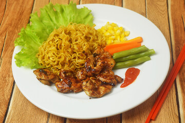 Fried noodles with black pepper seasoned Chicken Steak on a wooden table