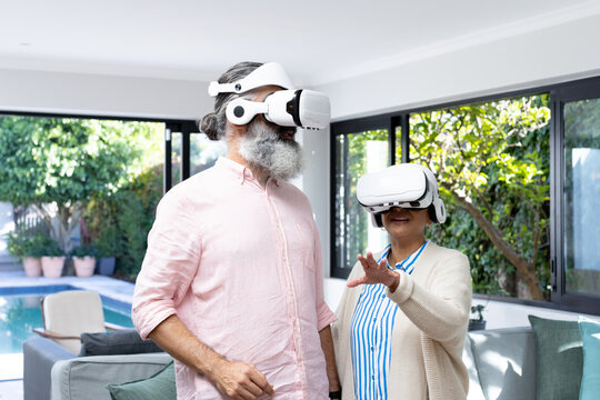 Senior couple using VR headsets, exploring virtual reality in living room