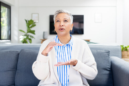 Senior woman sitting on couch, using sign language for communication