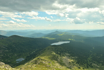 A picturesque valley sandwiched in the mountains and two picturesque lakes separated by a mountain range on a cloudy summer day.