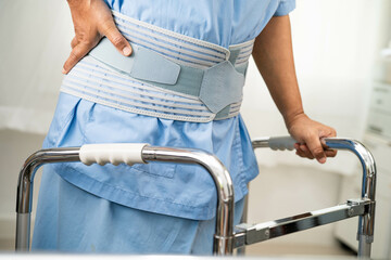 Asian woman patient wearing back pain support belt for orthopedic lumbar with walker.