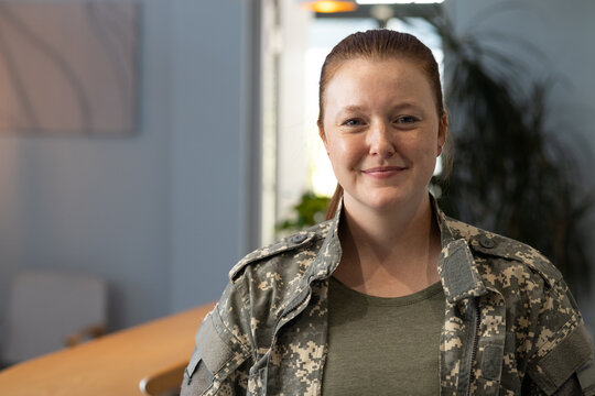 Smiling woman in undefined uniform standing indoors, looking at camera, copy space