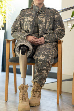 Military soldier personnel with prosthetic leg sitting on chair, wearing camouflage uniform