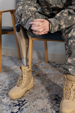 Sitting in uniform, soldier with prosthetic leg resting hands on lap