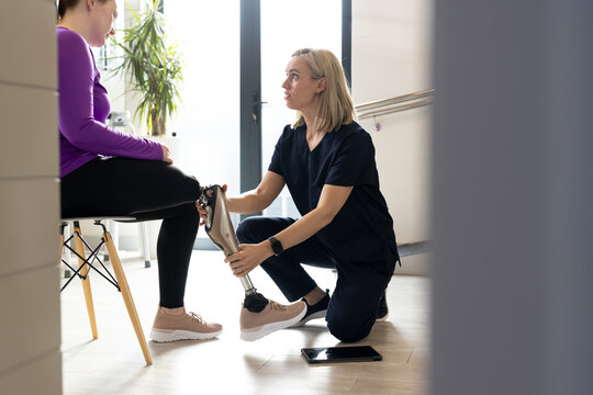 Physical therapist fitting prosthetic leg for patient in rehabilitation clinic