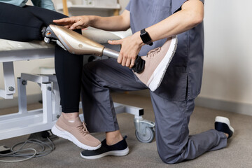 Adjusting prosthetic leg, technician assisting patient in medical medical clinic setting