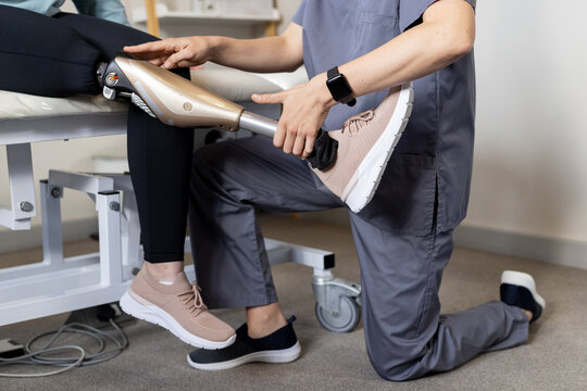 Adjusting prosthetic leg, technician assisting patient in medical medical clinic setting