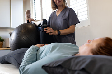 Physical therapist assisting patient with prosthetic leg using exercise ball