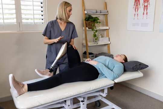 Physical therapist adjusting prosthetic leg for woman lying on examination table