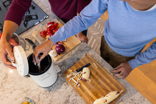 Preparing meal, men peeling potatoes and discarding scraps in kitchen