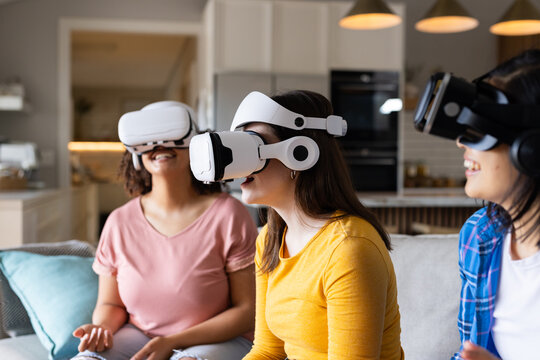 Using VR headsets, three women friends enjoying virtual reality experience at home