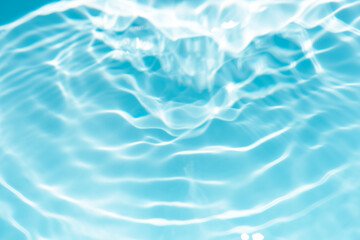Blue water with ripples on the surface. Defocus blurred transparent blue colored clear calm water surface texture with splashes and bubbles. Water waves with shining pattern texture background.