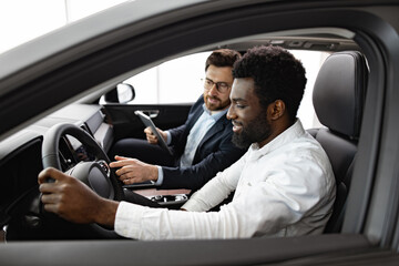 Happy customer learns about new car purchase from professional dealer in showroom. Caucasian car...