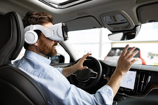 Man interacts with virtual reality headset while sitting inside modern vehicle, showcasing advanced automotive technology. Integration of VR in driving experience highlights innovation in cars.