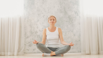 Peaceful mind. Domestic meditation. Home practice. Relaxed happy smiling woman in sportswear...