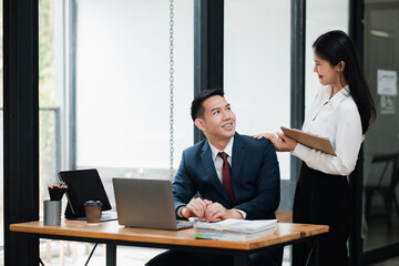 Two business professionals in a modern office setting, engaged in a discussion and collaboration, showcasing teamwork and productivity.