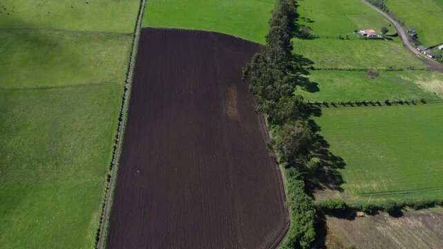 Drone flight over a brown field and the guitig neighborhood in canton mejia, Ecuador on a sunny day, dolly shot