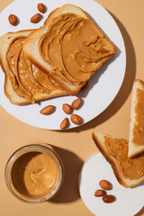 Peanut paste in a glass jar with toast, on a light background.