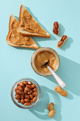 Peanut paste in a glass jar with toast, on a light background.